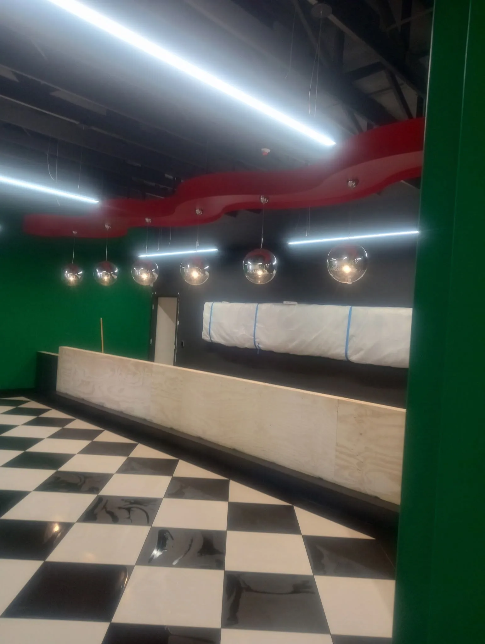Commercial space with a black and ivory checkerboard floor, dark walls, and pendant lighting